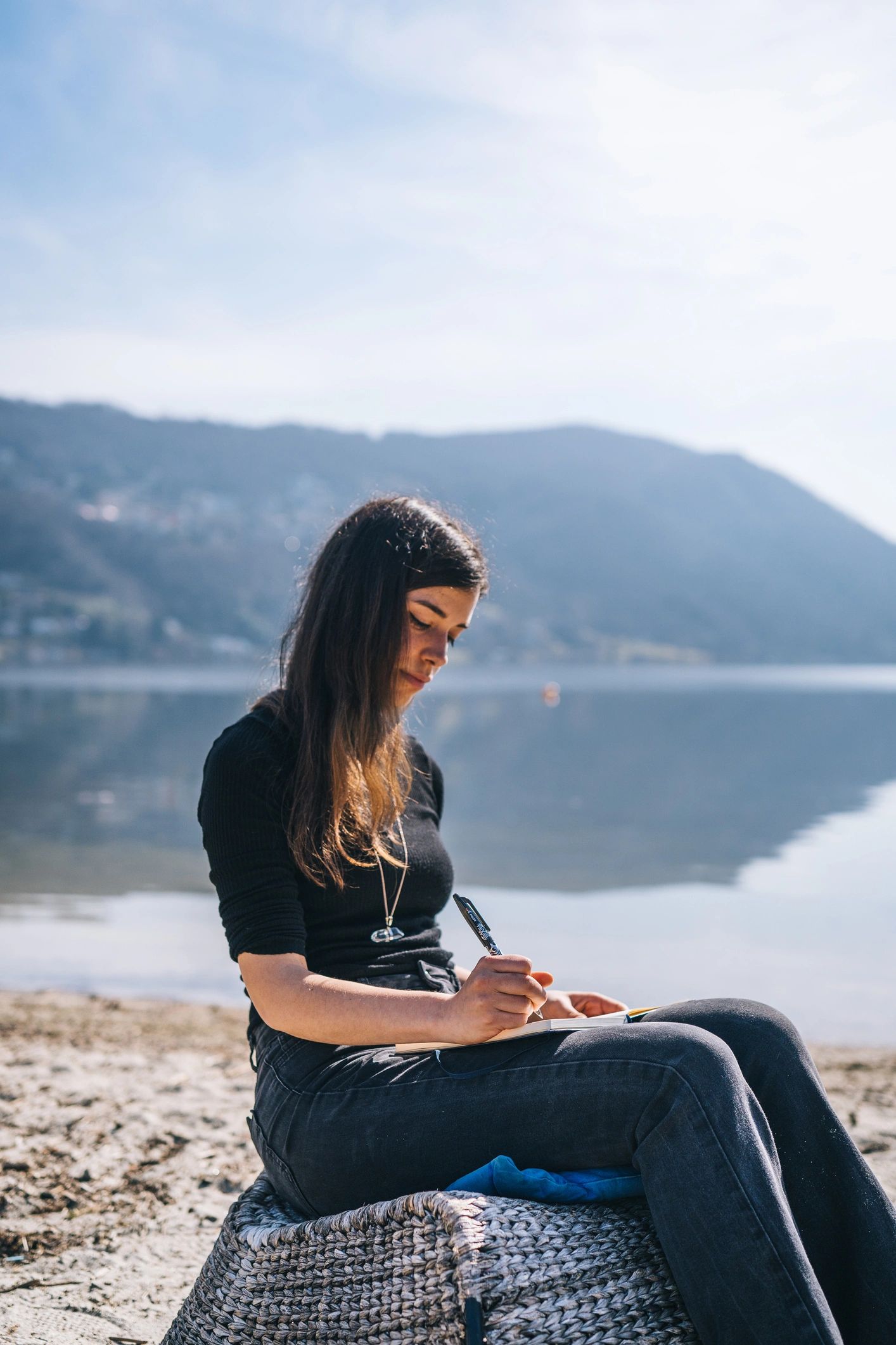 Person journaling by a lakeshore in the morning