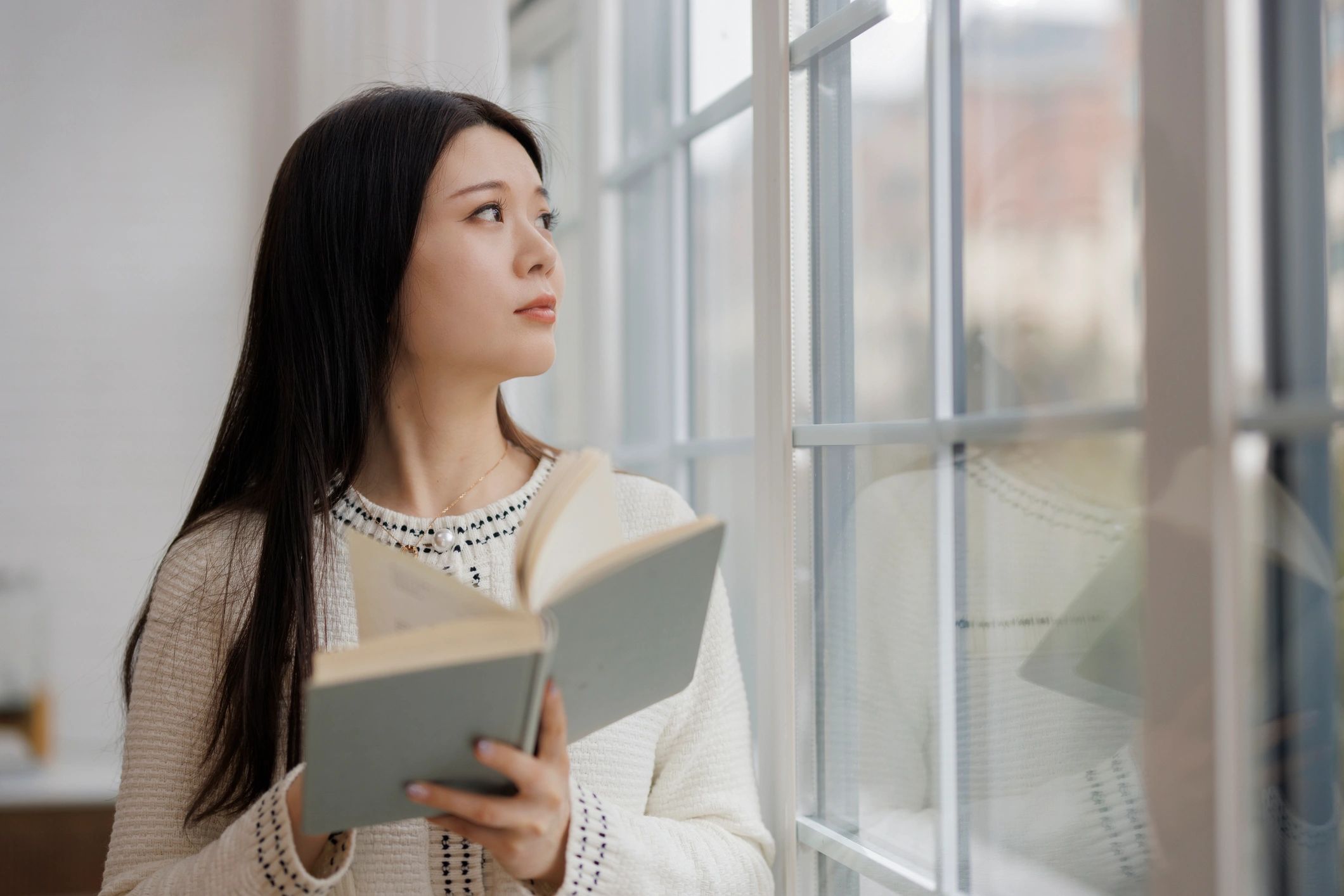 Woman reading by a window, calm reflective moment