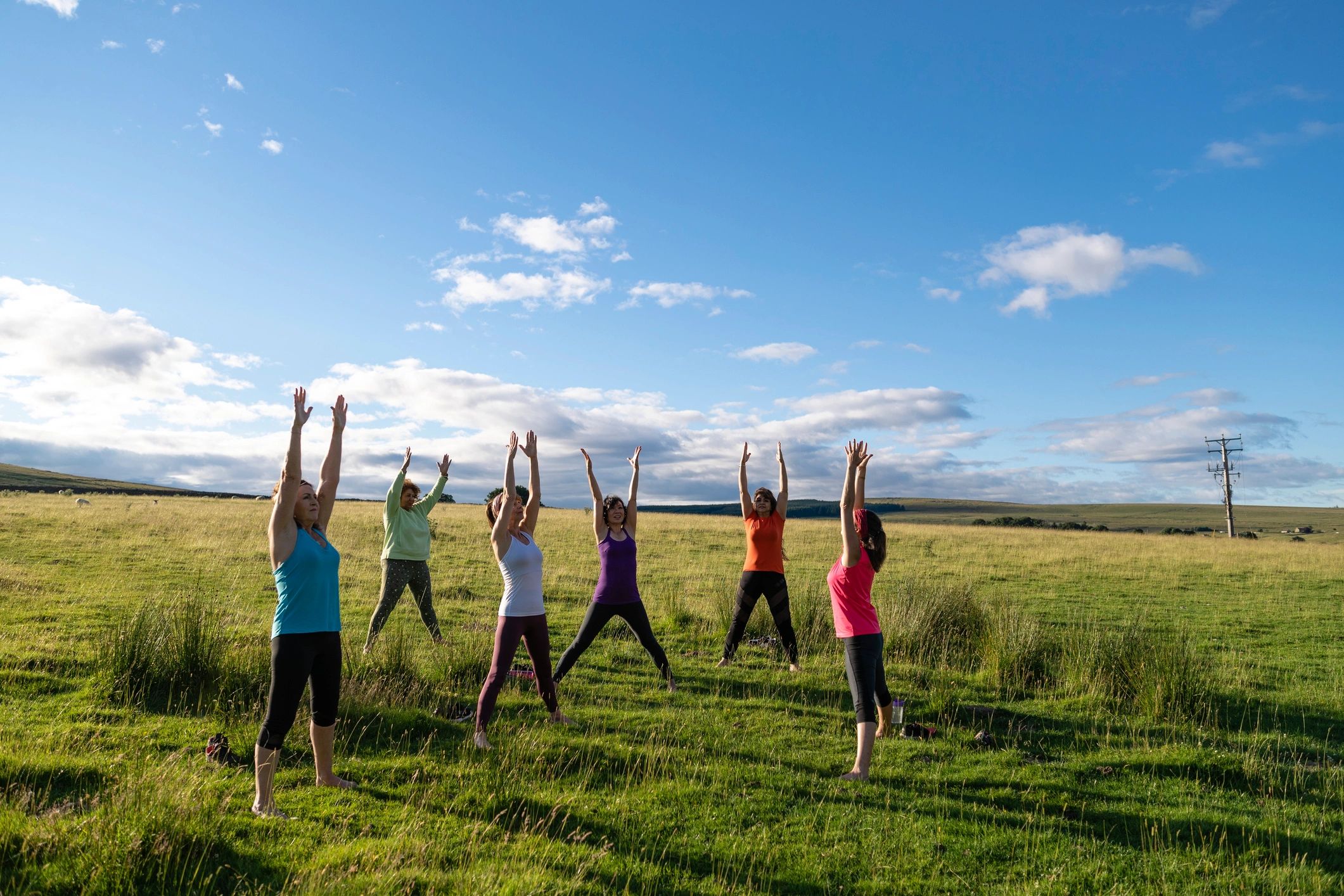 Group practicing yoga outdoors in morning sunlight