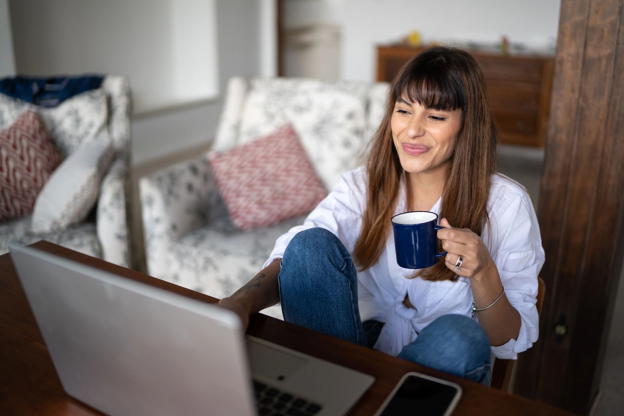 Person working calmly on a laptop at home with a warm drink
