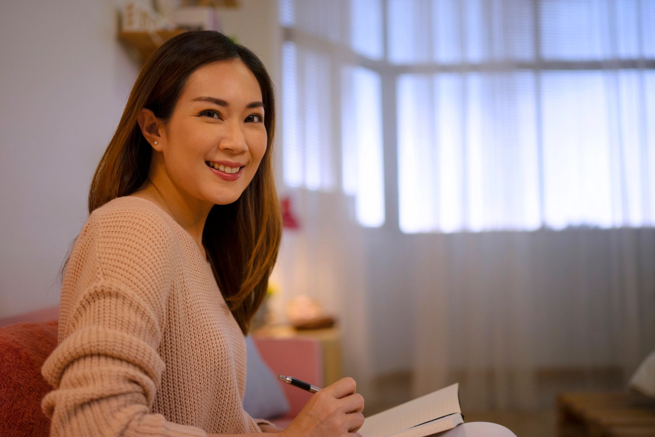 Woman journaling at home in warm window light