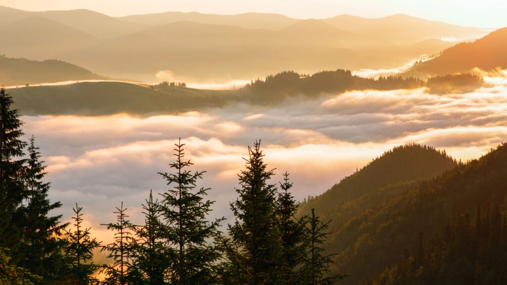 Floating clouds between mountains on the sunrise background