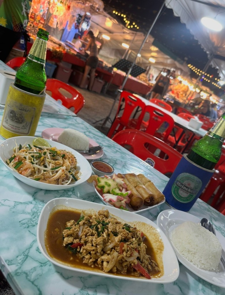 Thai food bowls and Chang beers on a table at a Thai Night Market in Koh Sumai
